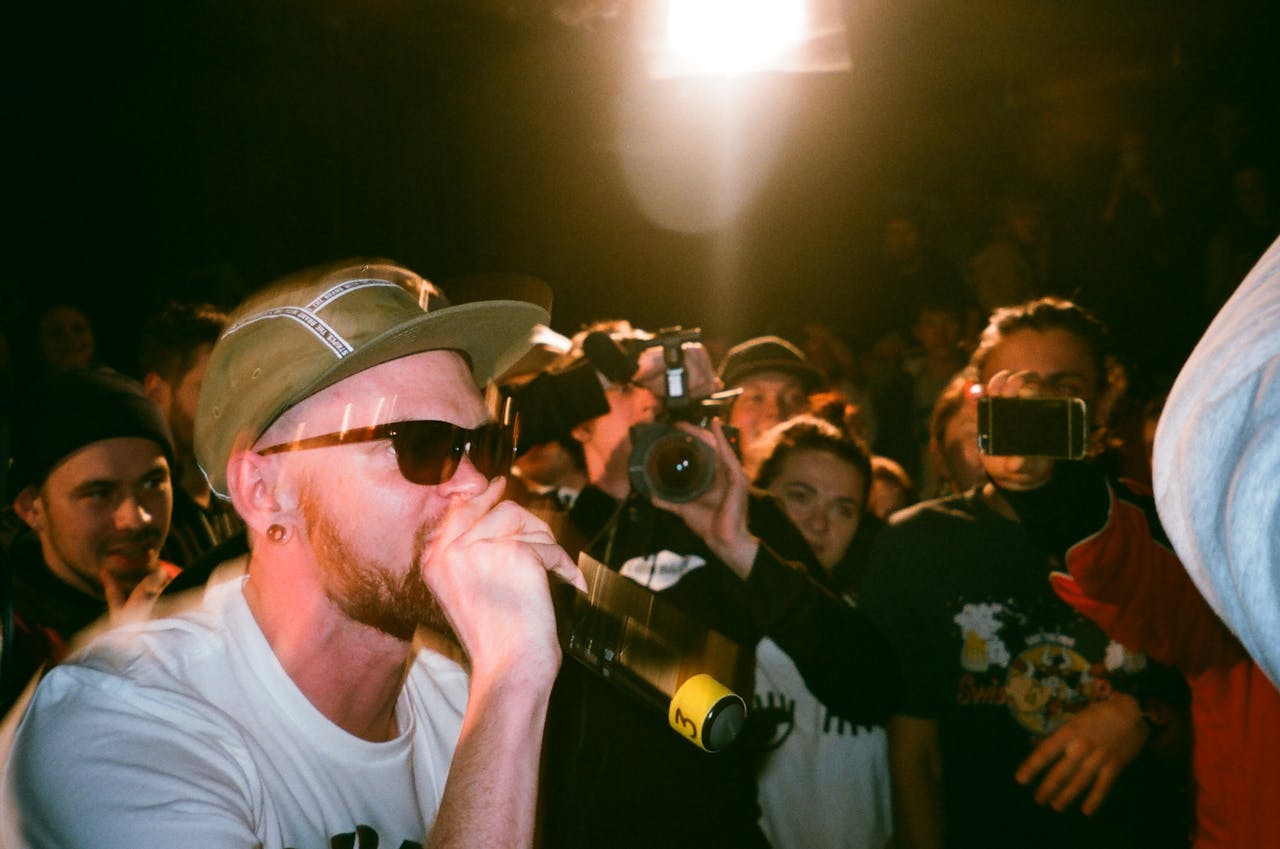 A rapper performs on stage with a vibrant crowd and bright spotlights.